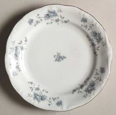 a white and blue plate with flowers on the rim is sitting on a gray surface