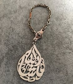 a metal keychain with an arabic calligraphy on it