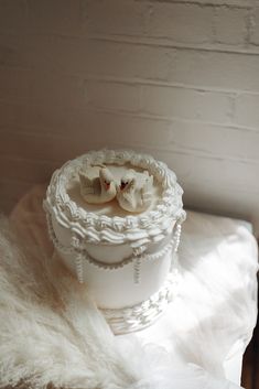 there is a small white vase with two flowers in it on the fur covered table