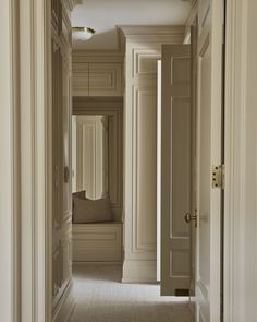 an open door leading to a hallway with white walls and beige carpeted flooring