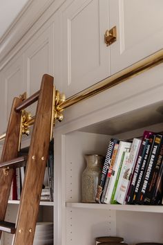 a book shelf with books on it and a ladder leaning up against the wall next to it