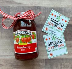 a jar of strawberry jam next to two tags