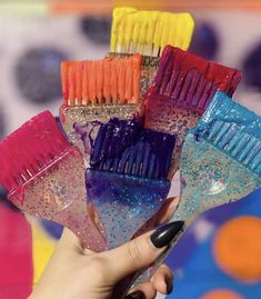 there are many different colored toothbrushes being held by a woman's hand