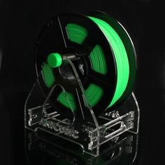 a spool of neon green filament on a clear stand with black background