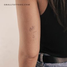 a woman's arm with a small flower tattoo on the back of her left arm