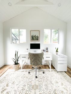 a white room with a rug, desk and chair