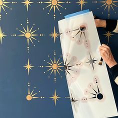 a person is holding up a piece of paper that has been drawn on it with gold stars in the background