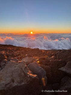 the sun is setting over some rocks on top of a mountain with clouds in the background