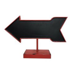 a black and red arrow sign sitting on top of a wooden stand