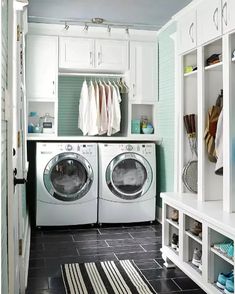 a washer and dryer in a laundry room with white cabinets, black tile flooring and open shelving