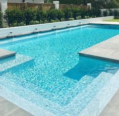 an empty swimming pool with blue water and steps leading up to the side walk area