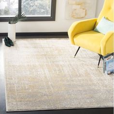 a yellow chair sitting on top of a wooden floor next to a white and gray rug