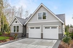 a house with two garages in front of it and landscaping around the driveway area