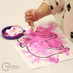 a child is painting with pink and black paint on the paper that has an elephant drawn on it