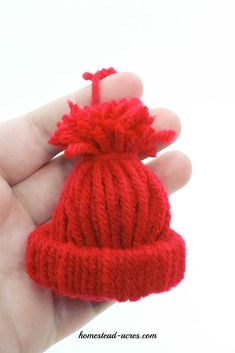 a small red knitted hat is held in the palm of someone's hand