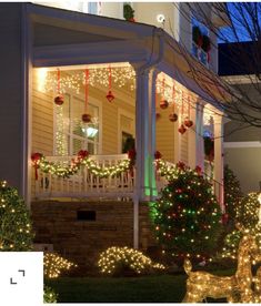 christmas lights are on the front porch of a house with deer statues and trees outside