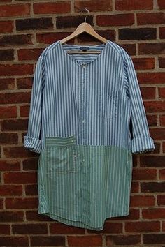 a blue and white striped shirt hanging on a brick wall