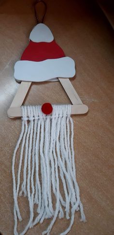 a santa hat on top of a piece of wood with white yarn hanging from it