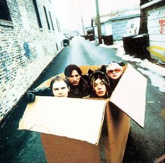 four people in a cardboard box on the street