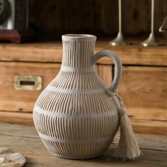 a white vase sitting on top of a wooden table