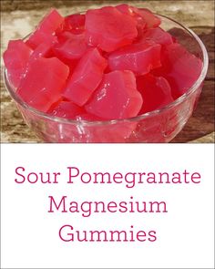 a glass bowl filled with red gummy bears on top of a wooden table next to text that reads sour pomegranate magnesum gummies