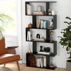 a room with a chair, bookshelf and plant in the corner on the floor