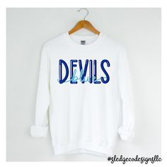 BLUE DEVILS | TUNICA ACADEMY | UNISEX SWEATSHIRT Cheer on your team in style with this Tunica Academy SWEATSHIRT! Show your team spirit, this one-of-a-kind hand-drawn crewneck is sure to impress! Please allow 2-3 WEEKS (NOT INCLUDING) business days for processing - THESE ARE MADE TO ORDER! If preorder - these we process after preorder date. - You will be notified by email on when your order is ready! We are located in Olive Branch. All our items are completely custom, and made to order for a uni Blue School Spirit Tops For Fall, Blue Tops For Fall School Spirit, Blue Collegiate Pre-shrunk Sweatshirt, Collegiate Blue Pre-shrunk Sweatshirt, Blue Team Spirit Sweatshirt With Team Name, Blue Varsity Top With Team Name, Blue Pre-shrunk School Spirit Sweatshirt, Blue Long Sleeve Tops With Team Logo, Blue Relaxed Fit Sweatshirt For Game Day