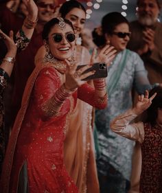 a woman in a red sari taking a selfie with her friends and family