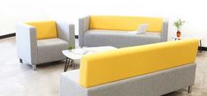 two gray and yellow couches sitting next to each other in a room with white walls