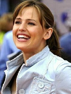 a woman smiling and wearing a blue shirt