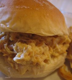 a close up of a sandwich on a plate with onion rings and meat in the middle