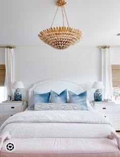 a bedroom with a bed, dressers and chandelier hanging from the ceiling