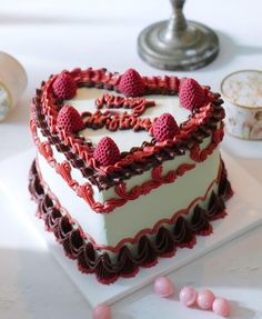 a heart shaped cake with raspberries in the shape of a heart on a plate