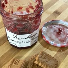 a jar of jam sitting on top of a wooden cutting board next to a cookie