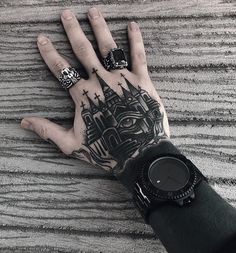 a person's hand with tattoos on it and a watch in the other hand