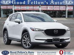 a white mazda cx - 5 is parked in front of a dealers showroom