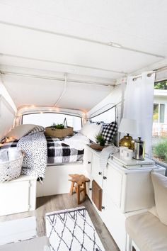 the interior of a camper van with white walls and wood flooring is decorated in black and white