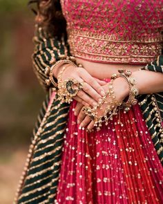 a woman in a red and green lehenga holding her hands on her chest