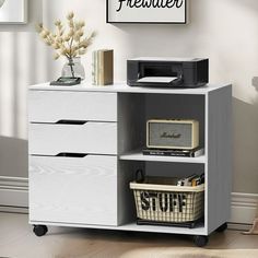 a white cabinet with two drawers and a printer on the top shelf next to it