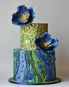 a three tiered cake decorated with blue flowers and green icing on a black background