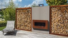 a fire place sitting on top of a wooden deck next to a wall covered in logs