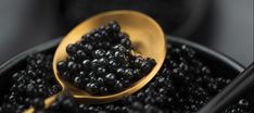 a wooden spoon filled with blackberries on top of a table