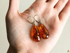 "Natural Baltic amber cognac color earrings is a perfect choice for classy style admirers! Perfect choice to brighten up office outfit or look even more beautiful on a special occasion! Shaped in drop form these earrings look delicate yet fancy. MATERIALS AND SIZE: Stone: 100% Natural Baltic Amber Findings: sterling silver 925 Earrings A: Weight: 6 g (0,21 oz) Bead size: 2,8 cm (1,1 in) x 1,4 cm (0,55 in) Total earring length: 4.9 cm (1,92in) Earrings B: Weight: 5,49 g (0,20 oz) Bead size: 2,3 c Classic Orange Earrings For Formal Occasions, Handmade Orange Earrings For Formal Occasions, Handmade Teardrop Earrings For Formal Occasions, Elegant Brown Hypoallergenic Earrings, Brown Teardrop Earrings For Formal Occasions, Classic Amber Earrings For Formal Occasions, Elegant Brown Drop Earrings, Elegant Brown Teardrop Earrings For Gift, Formal Brown Teardrop Earrings