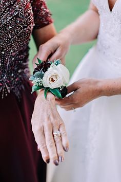 two women in wedding dresses holding hands with flowers on their fingers and the bride's bouquet