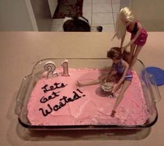 two barbie dolls on top of a pink birthday cake with the number one written on it