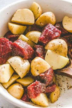 a white bowl filled with potatoes and meat