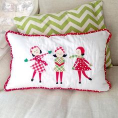 two decorative pillows on a white couch with green and red chevroned pillow cases