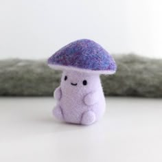 a small purple mushroom sitting on top of a white table next to a gray pillow