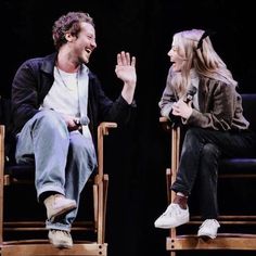 two people sitting in chairs and one is holding his hand out to the other person