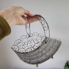 a person is holding a metal basket with two leaves on the bottom and one in the middle